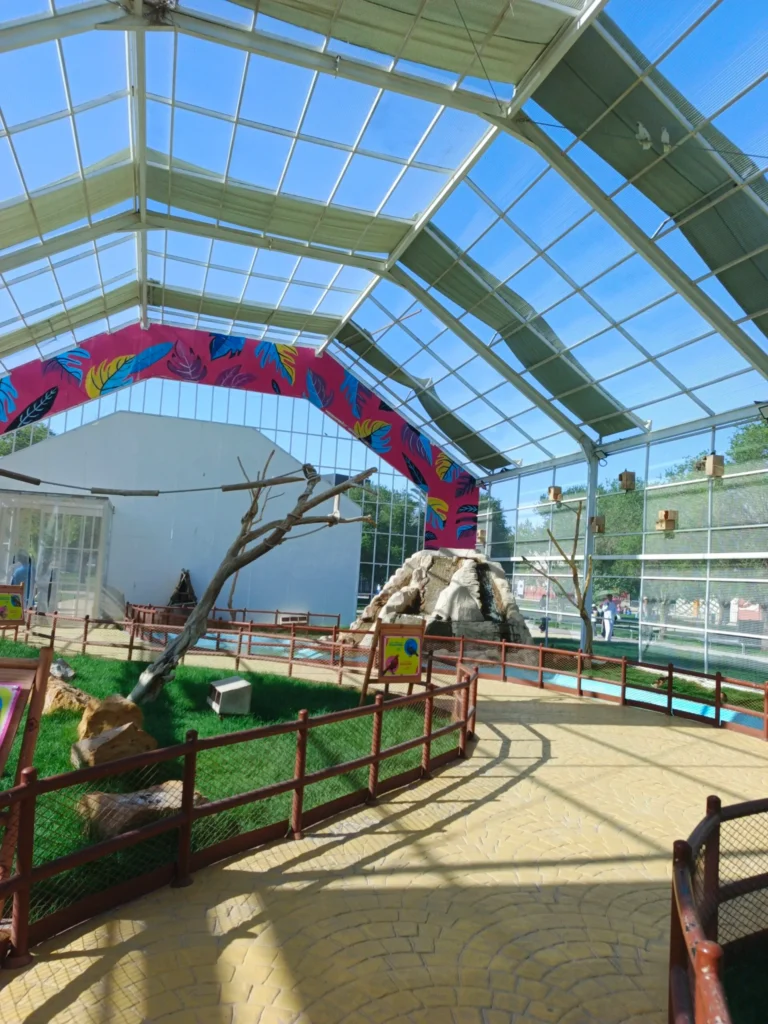 Large indoor bird aviary at Riyadh Zoo with dome roof tropical leaf arch decoration and rock formation habitat for birds