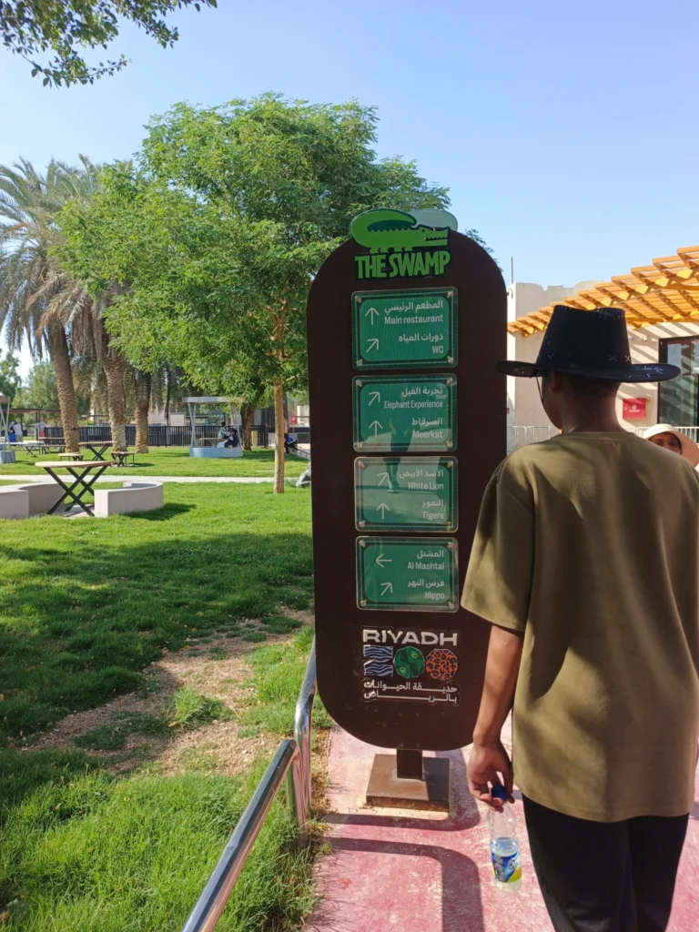 The Swamp zone bilingual directional signboard at Riyadh Zoo pointing toward White Lion Tigers Elephant Experience and Hippo sections