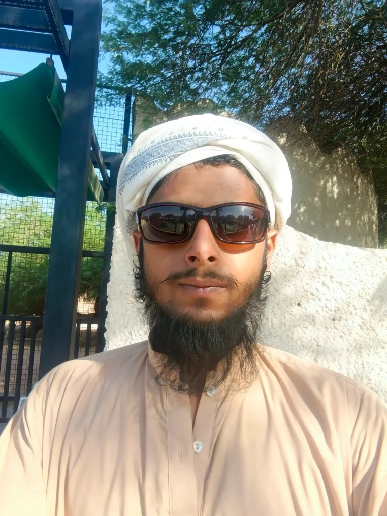 Expat visitor at Riyadh Zoo entrance wearing shalwar kameez and white shawl with sunglasses for summer heat protection